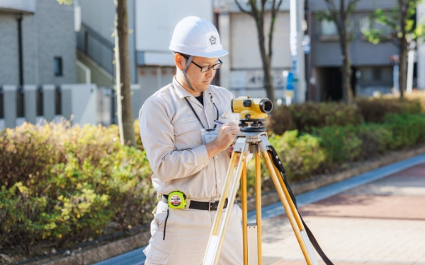 測量機でメモを取っている建設部 道路課の人の画像